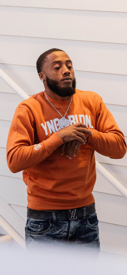 Discover elevated comfort and style with the YNG & BLDN ARCH Premium Crewneck Sweatshirt by Young and Building. Elevate your wardrobe with this high-quality, fashion-forward piece designed for the modern hustler. Upgrade your fashion game with the premium pullover in burnt orange, yam orange color with white puff print