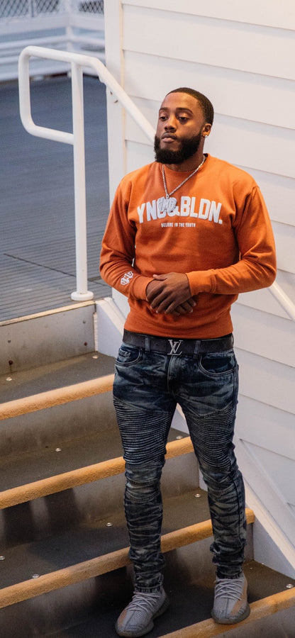 Discover elevated comfort and style with the YNG & BLDN ARCH Premium Crewneck Sweatshirt by Young and Building. Elevate your wardrobe with this high-quality, fashion-forward piece designed for the modern hustler. Upgrade your fashion game with the premium pullover in burnt orange, yam orange color with white puff print