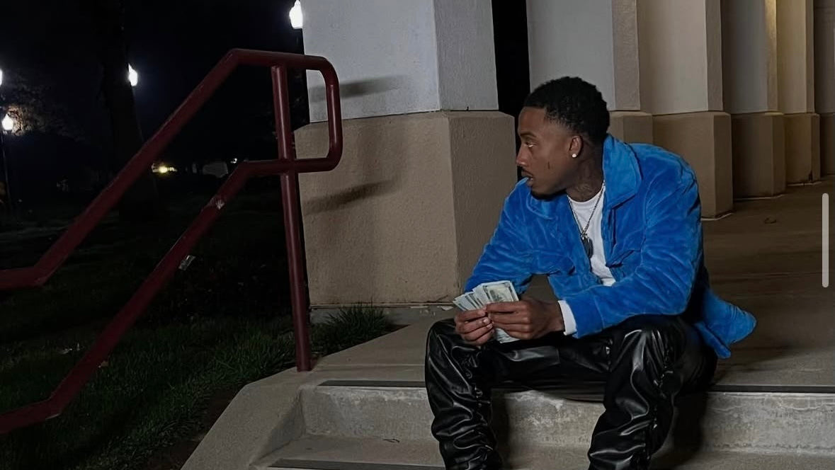 Person sitting on steps at night holding money